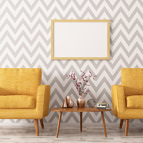 Salon avec deux fauteuils en tissu jaune, une table basse et de la tapisserie au mur avec un cadre